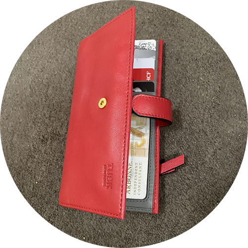 Red wallet with cards and cash peeking out, resting on a textured surface.