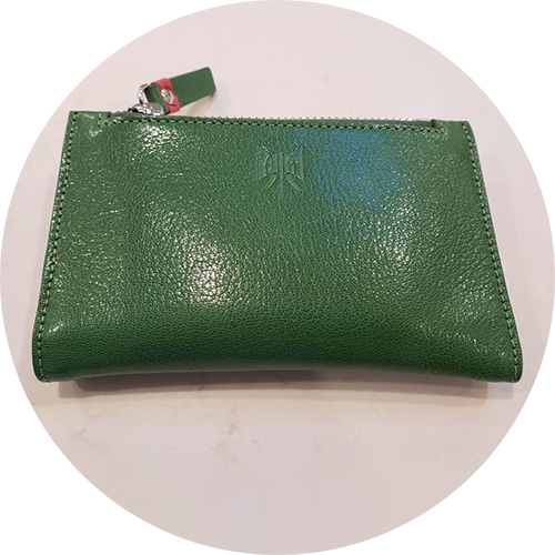 Green leather pouch with a zipper on a white marble countertop.