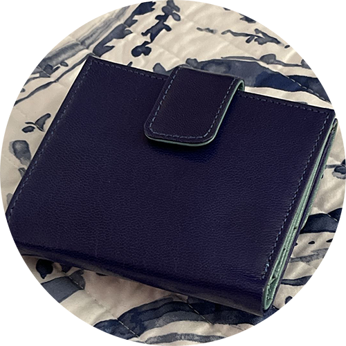 Closed navy wallet on a patterned fabric surface.