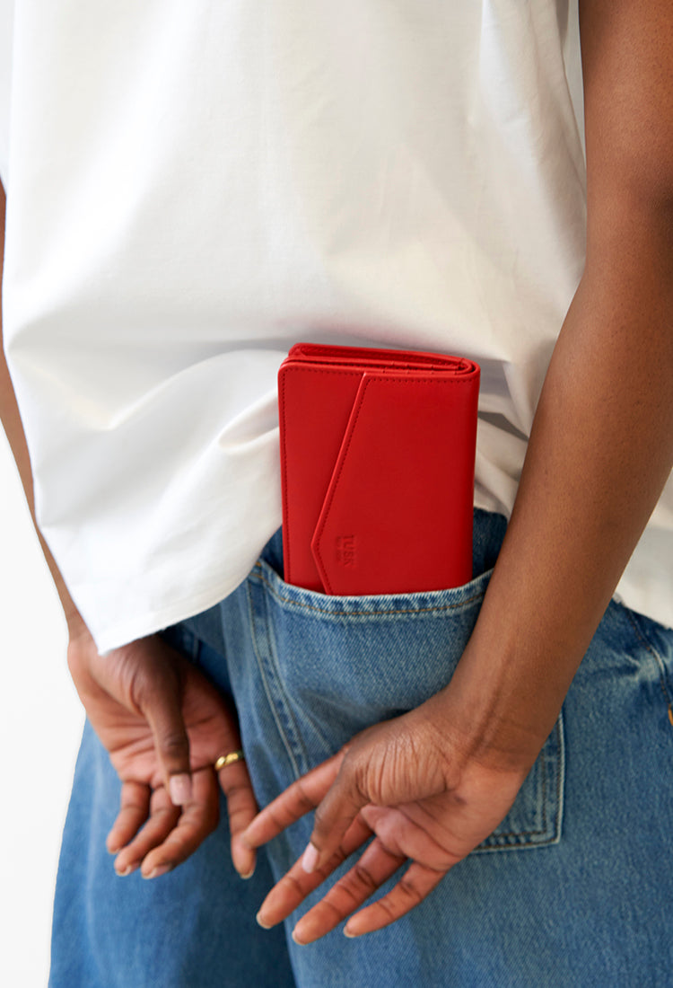 Person in white top and blue jeans with a red wallet in their back pocket.
