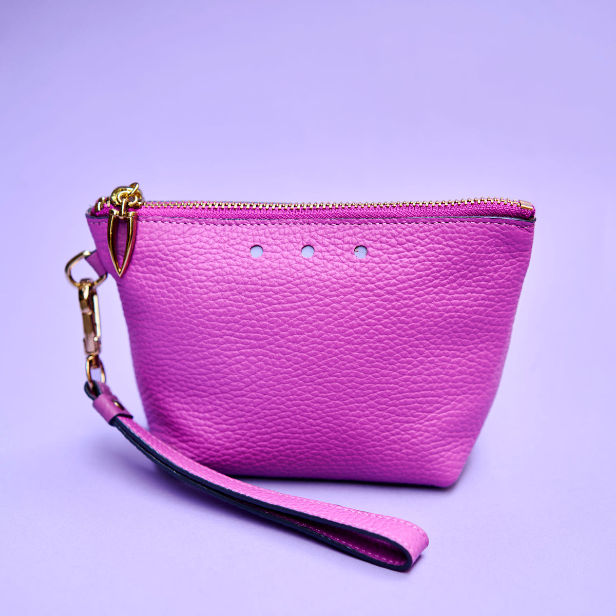 Purple wristlet cosmetic pouch with gold zipper on a purple background - MAGENTA