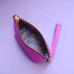 Open purple wristlet cosmetic pouch with gold zipper on a light purple background - MAGENTA