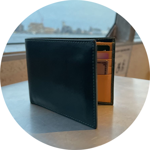Black leather wallet with visible cards inside on a table with a blurred background.