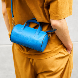 Person wearing a mustard yellow outfit with a blue handbag on a light background - AZURE