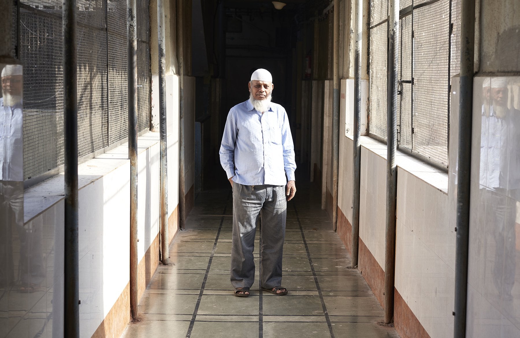 KHALIL stand in a sunlit corridor with reflective walls.