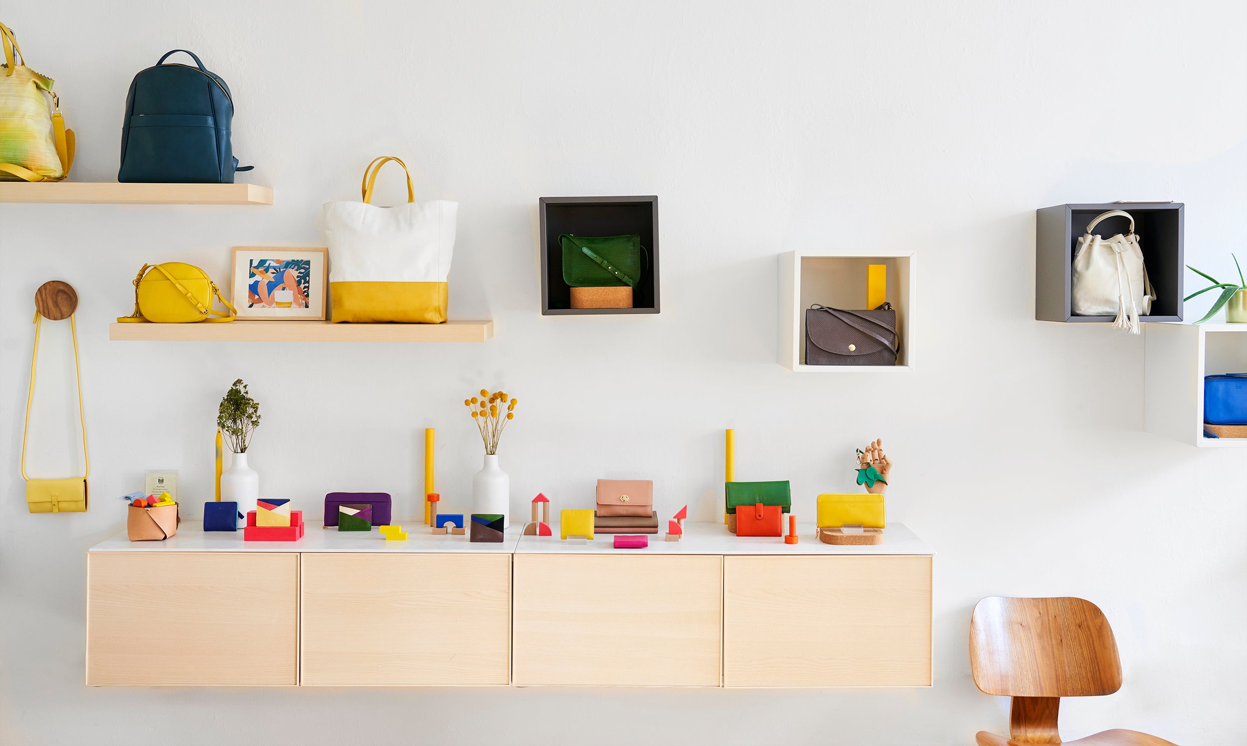 Interior wall display featuring shelves with bags, small colorful items, and wooden furniture.