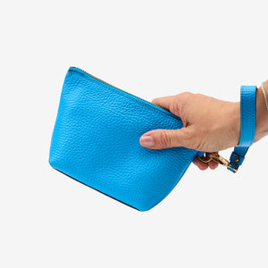 Hand holding a blue cosmetic beauty pouch against a white background - AZURE
