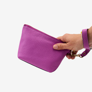 Purple cosmetic beauty pouch held by a hand on a white background - MAGENTA