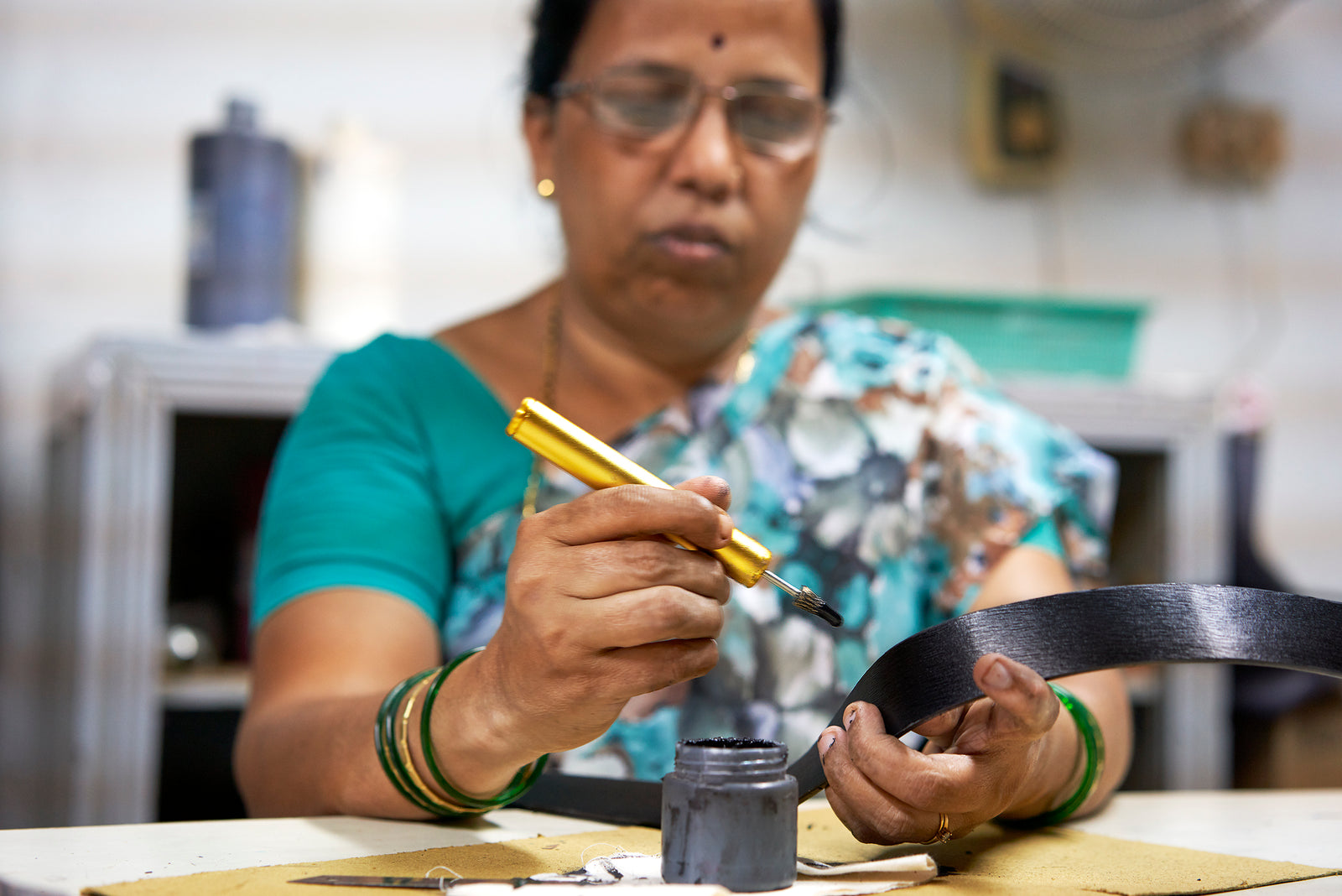 A person holds a paintbrush and tape, preparing for a creative project, embodying artistry and craftsmanship at home.