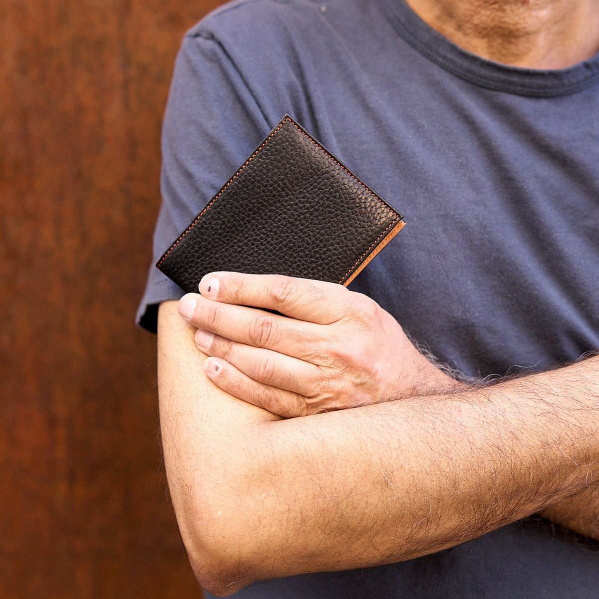 Man with folded arms black pebble grain leather billfold - BLACK