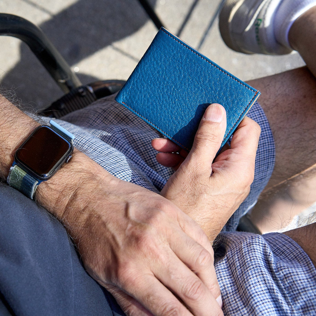 Man holding blue pebble grain leather billfold - DENIM