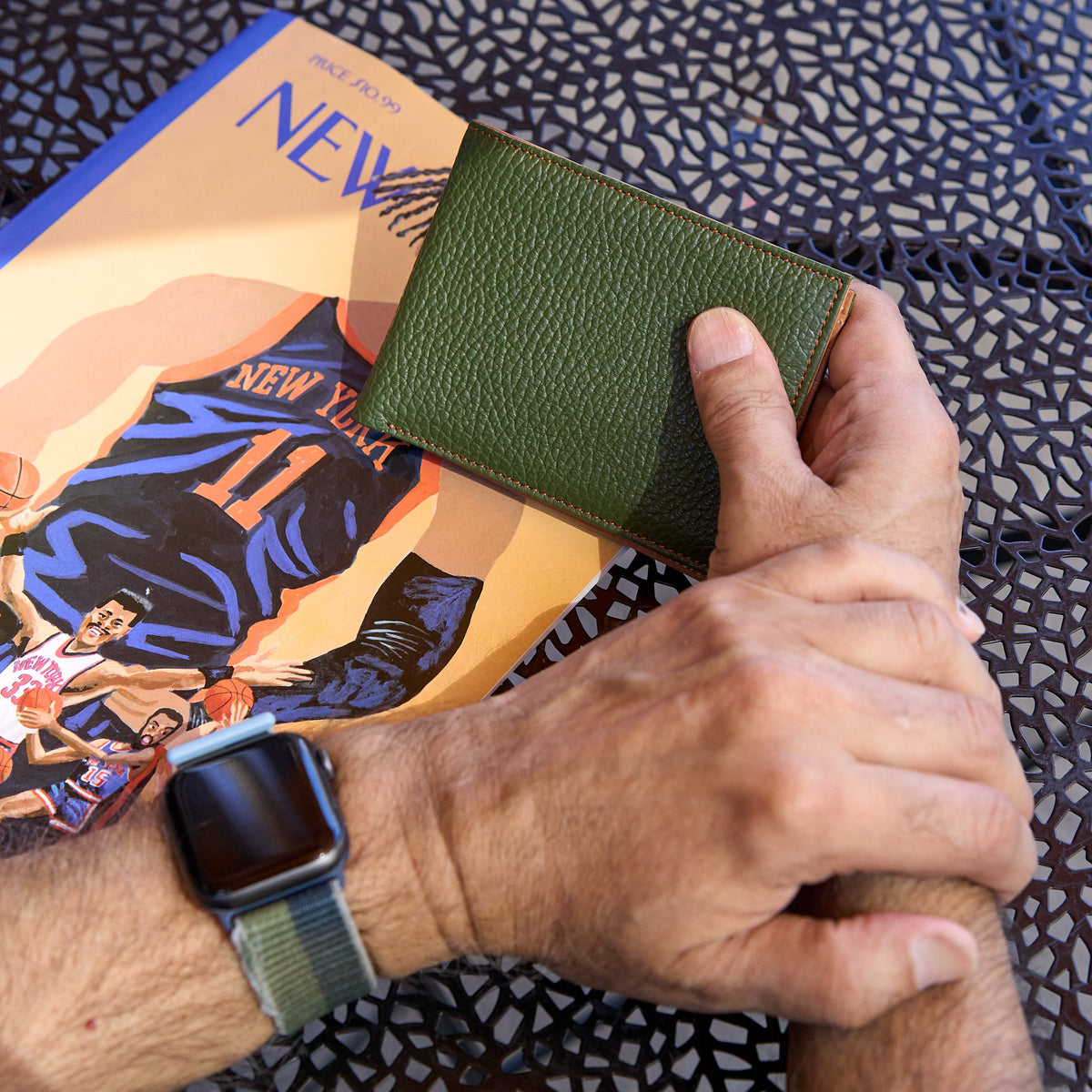Man holding green pebble grain leather billfold - FOREST