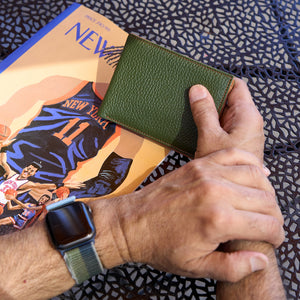Man holding green pebble grain leather billfold - FOREST
