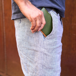 Man inserfting green pebble grain leather billfold in pant pocket - FOREST