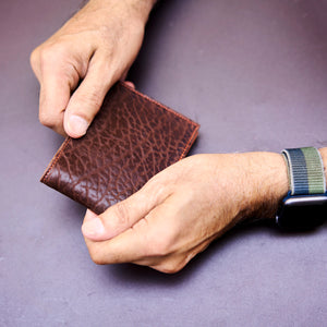 Man holding brown pebble grain leather billfold  - CHOCOLATE