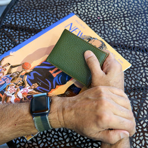 Man holding green pebble grain leather billfold - FOREST