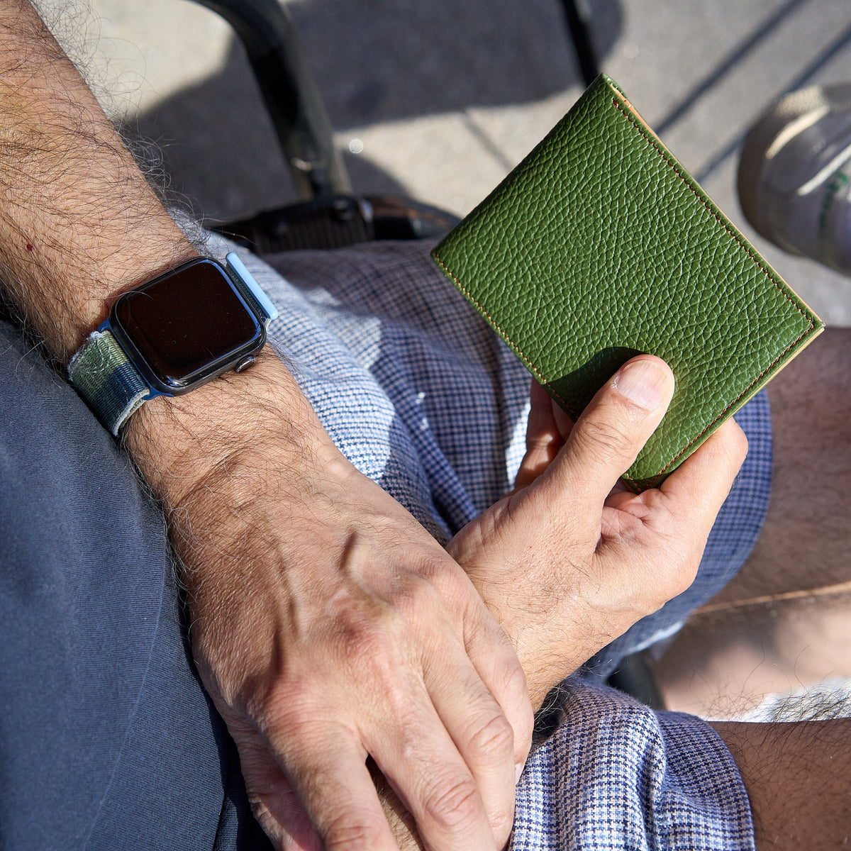Man holding green pebble grain leather billfold - FOREST