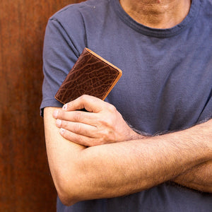 Man holding brown pebble grain leather card case - CHOCOLATE