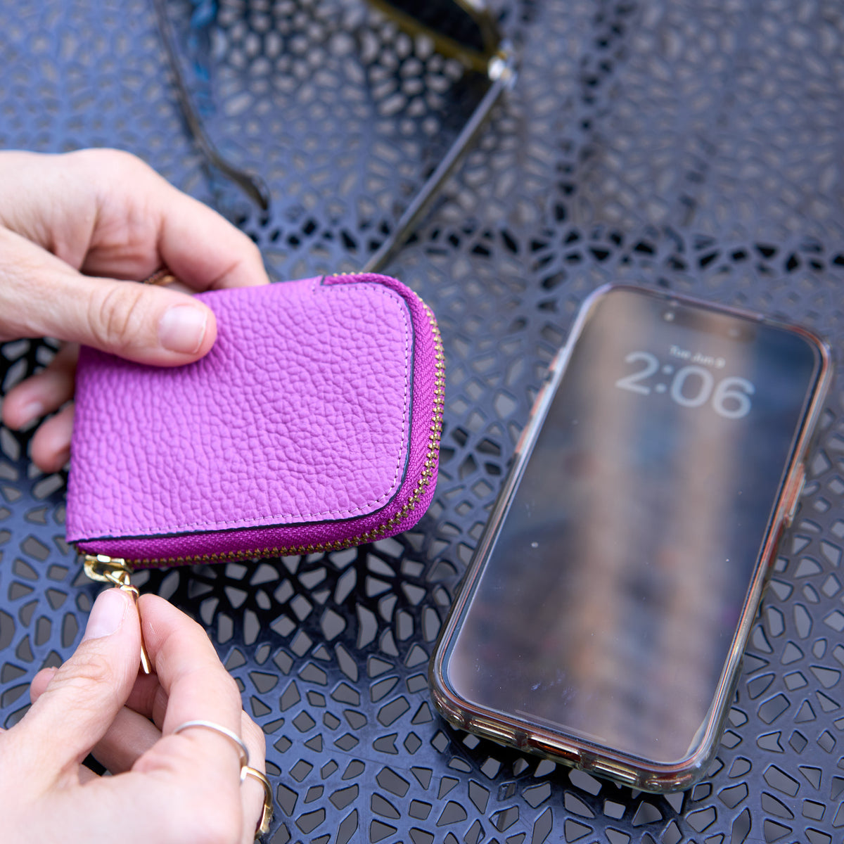 Tusk 194 Ascot small zip card wallet, being unzipped beside a phone - MAGENTA