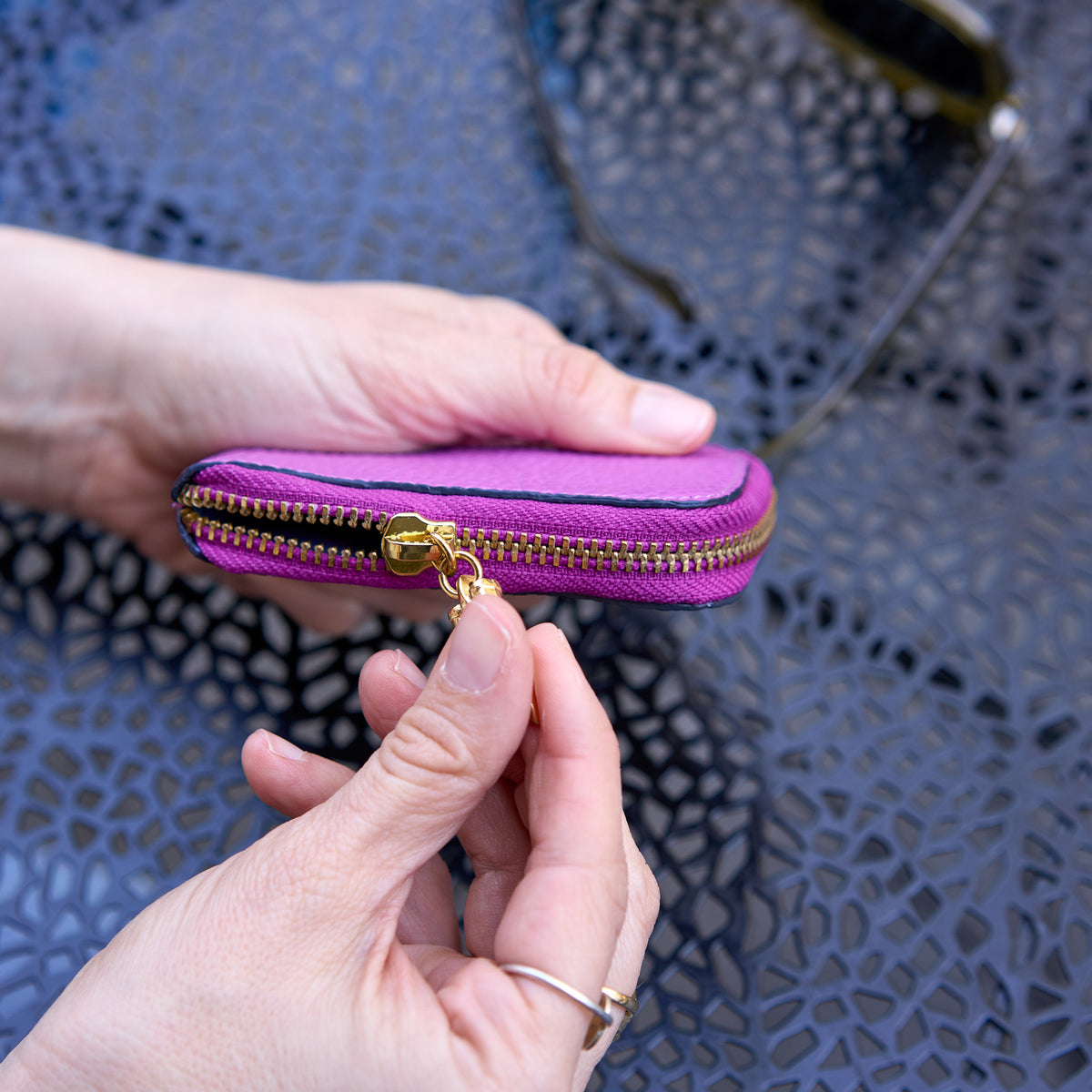 Tusk 194 Ascot small zip card wallet, side view showing the gold-tone zipper held in hand - MAGENTA