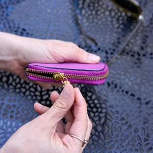 Tusk 194 Ascot small zip card wallet, side view showing the gold-tone zipper held in hand - MAGENTA