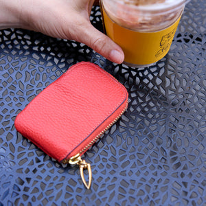 Tusk 194 Ascot small zip card wallet, beside an iced coffee on a cafe table - ORANGE