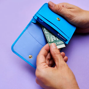 Blue leather wallet with money on a purple background - AZURE
