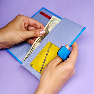 Person holding a blue wallet with money and cards on a purple background - AZURE