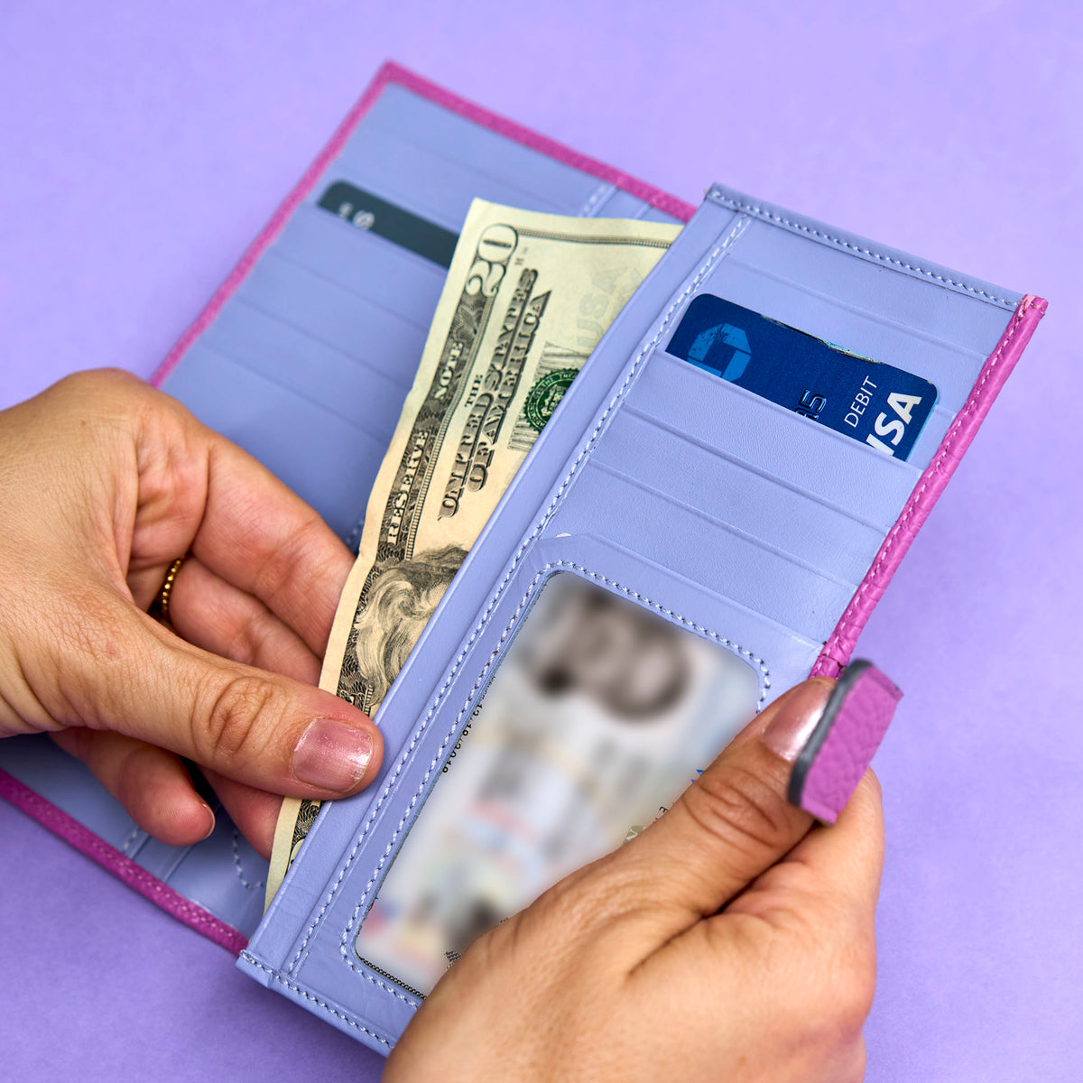 Magenta wallet with lavender interior held by hands against a purple background - MAGENTA