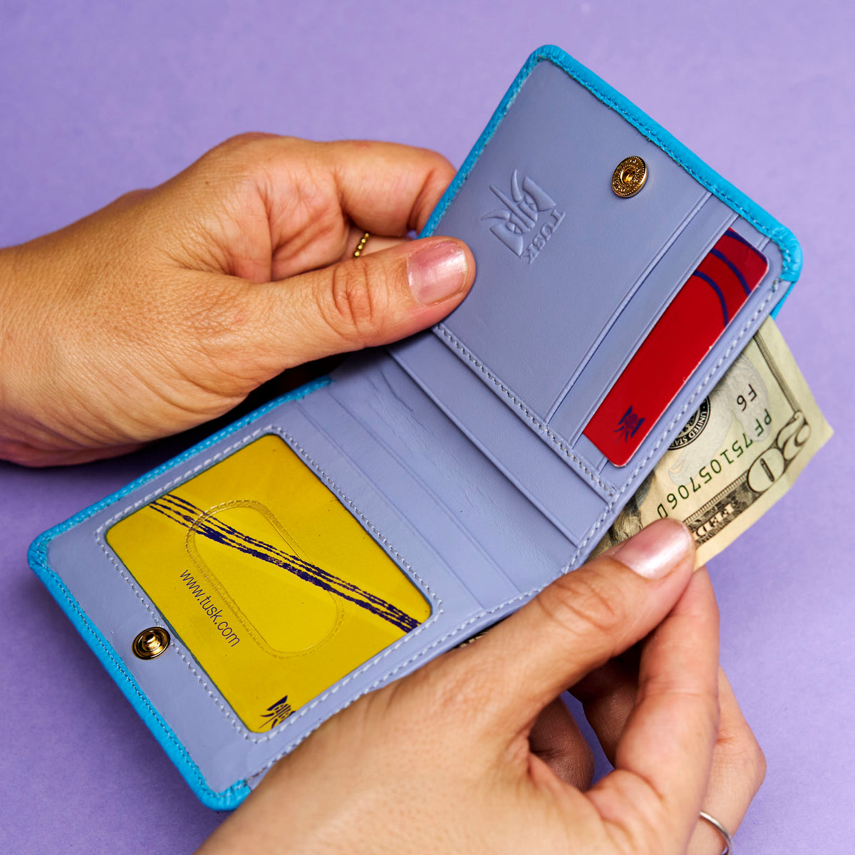 Blue leather wallet with cards and money on a purple background help open in hands - AZURE