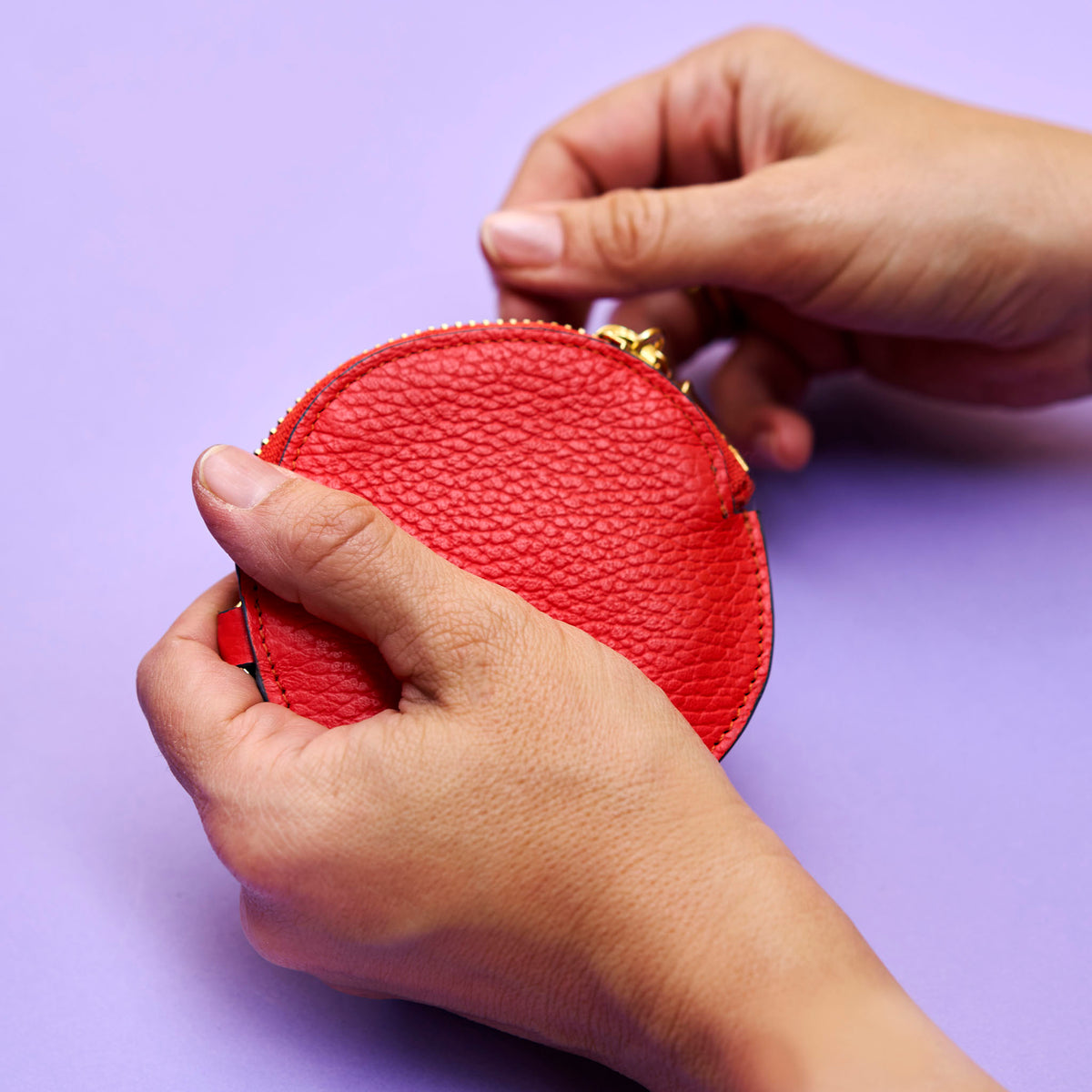 Orange leather round  charm held by hands against a purple background - ORANGE