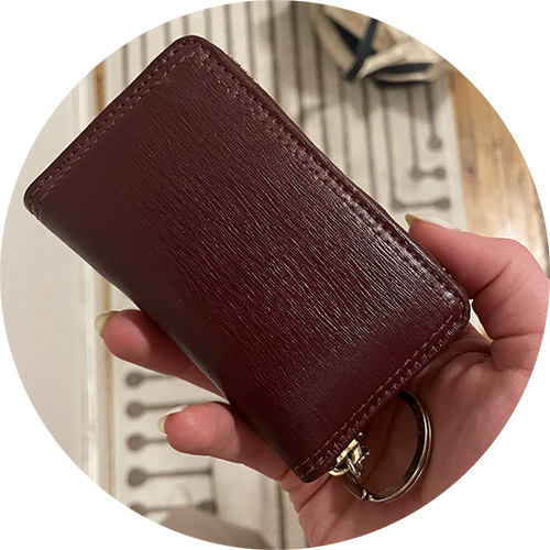 woman hand holding a maroon keychain wallet.