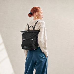 Person wearing a black backpack with a neutral background - BLACK