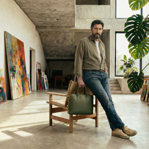 Man holding a green briefcase bag in an art gallery setting - FOREST