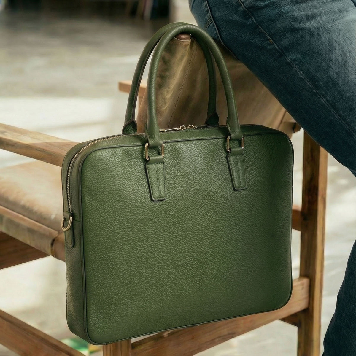 Green leather briefcase on a wooden chair with a blurred background - FOREST