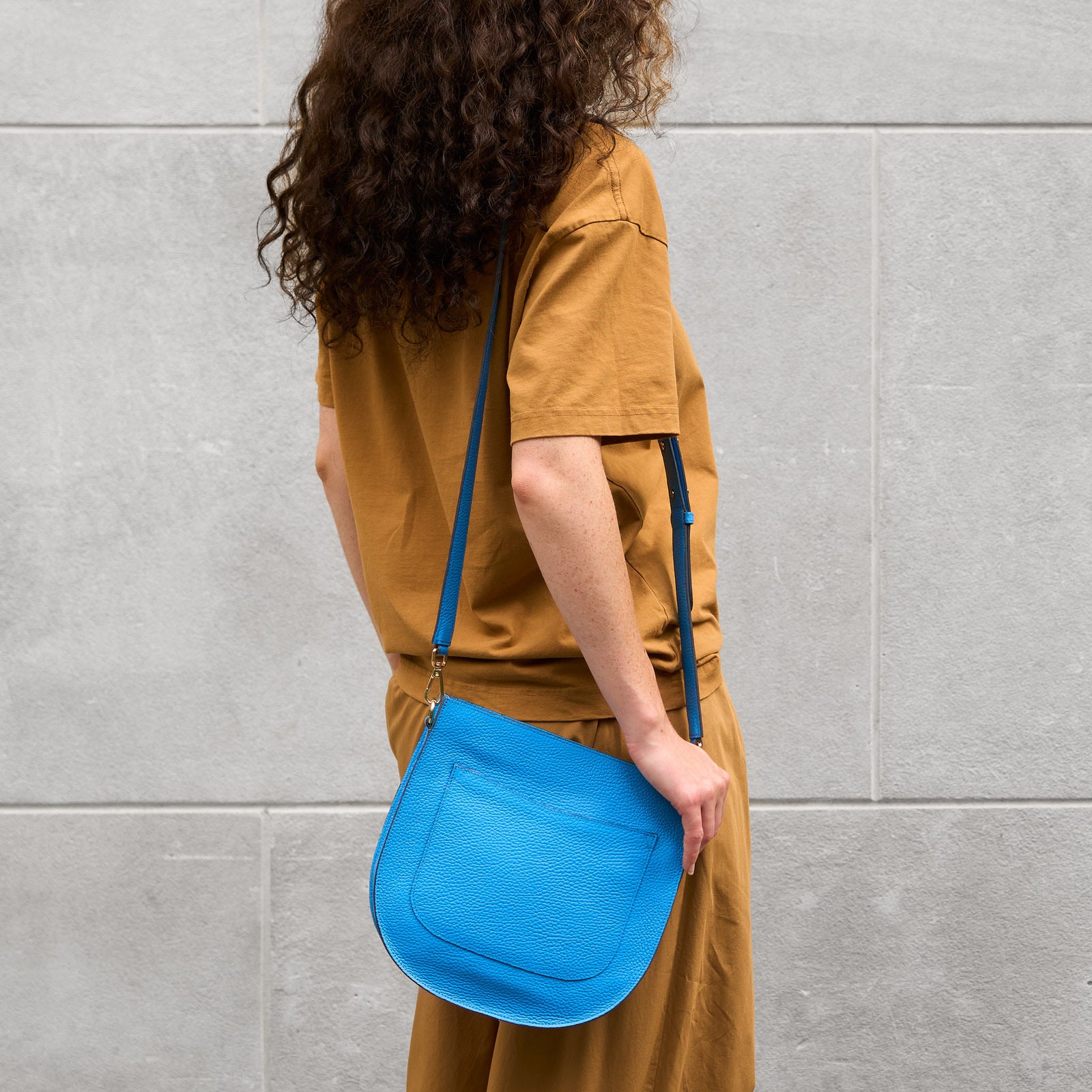 Blue italian leather handbag with a strap on a light gray background - AZURE