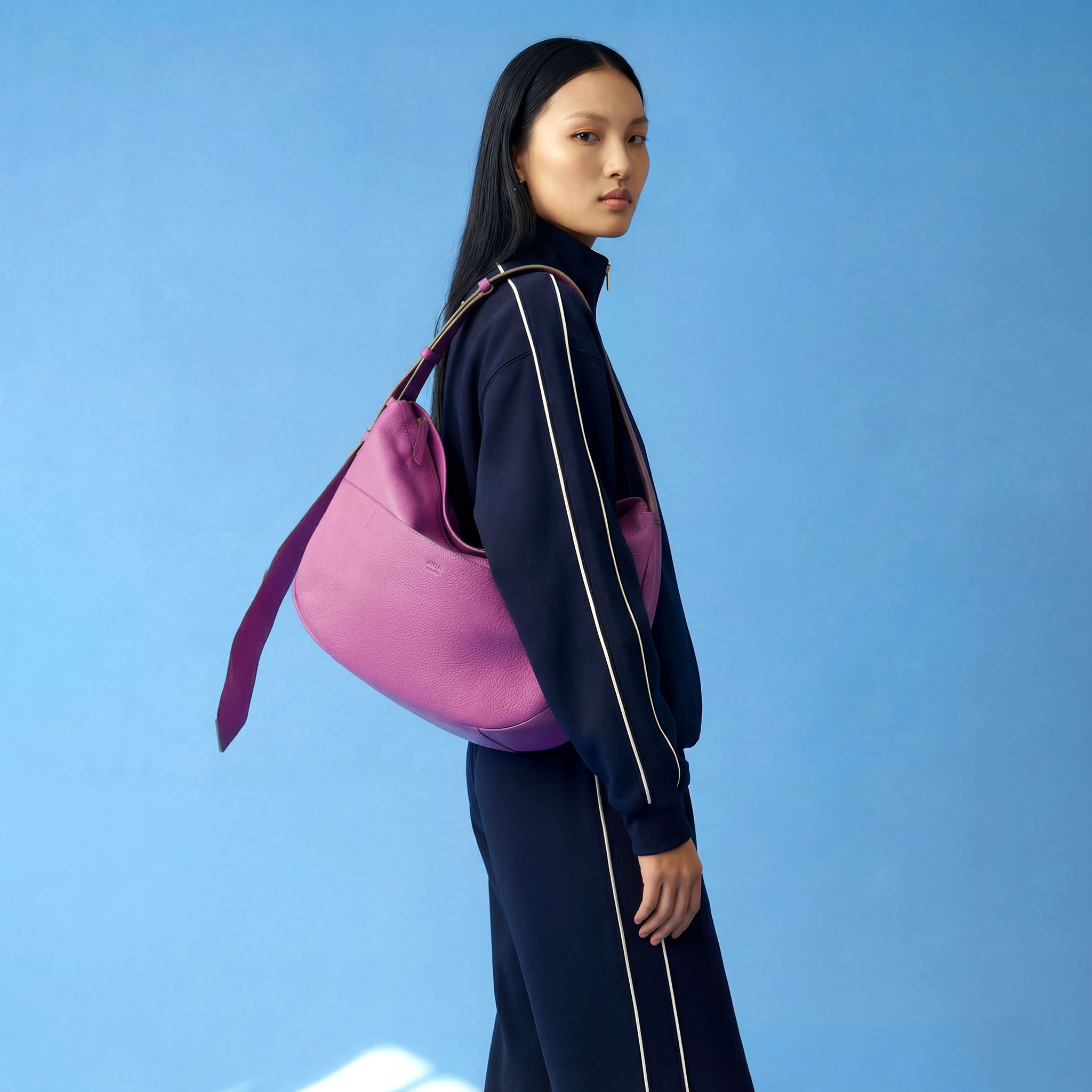 Woman holding a pink bag against a blue background - MAGENTA