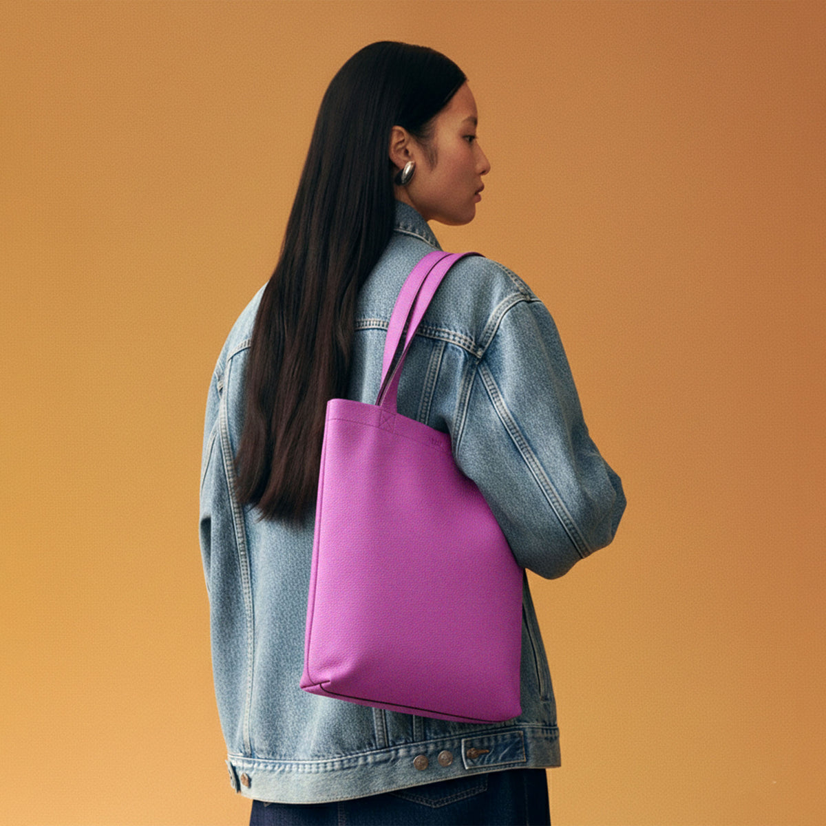 Person wearing a denim jacket with a pink tote bag on an orange background - MAGENTA