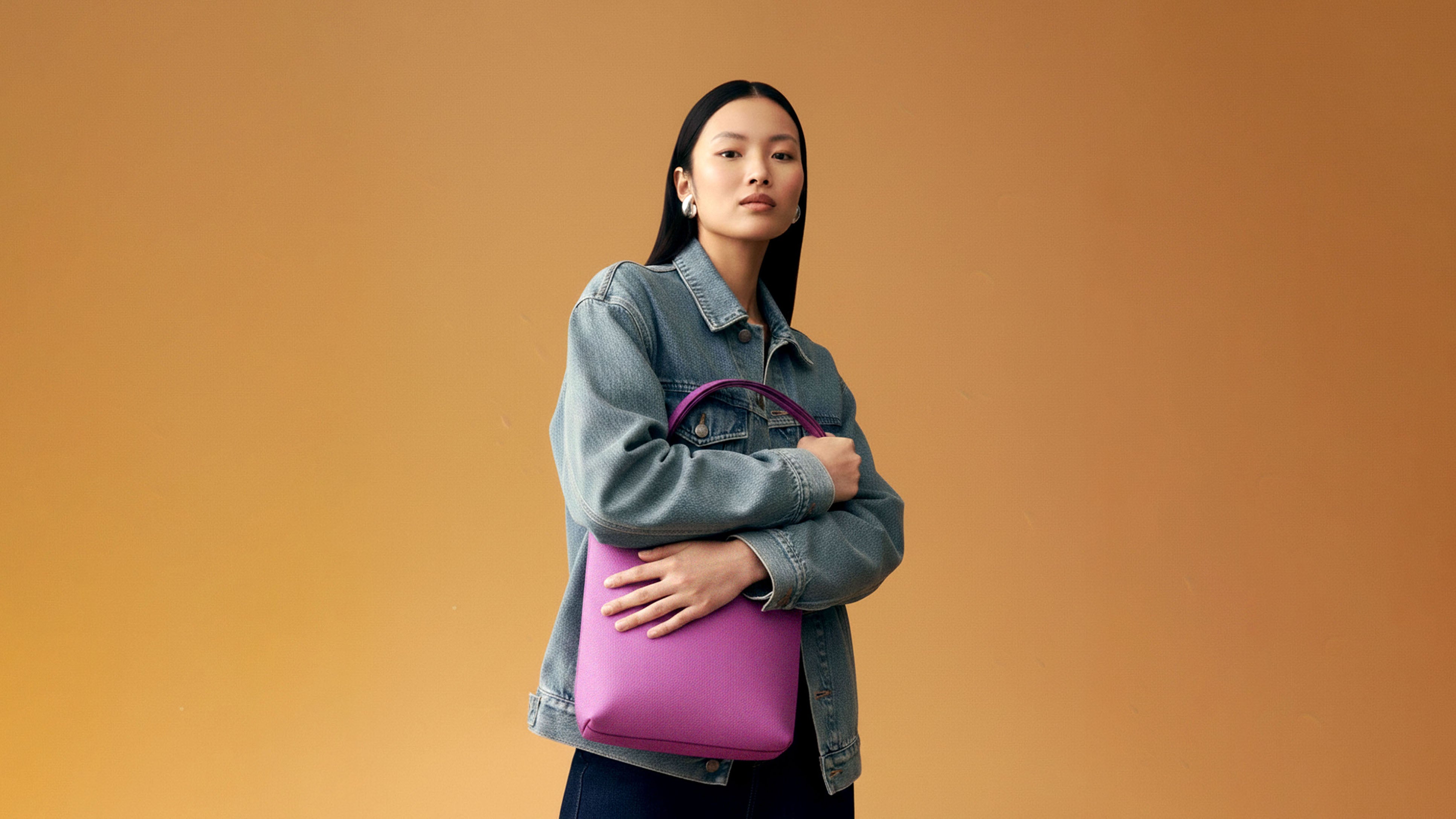 Woman holding a pink bag against an orange background