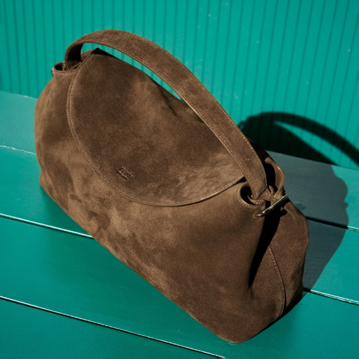 Brown suede handbag on a green surface - BROWN