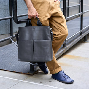 Person holding a gray leather bag on a city street - CHARCOAL