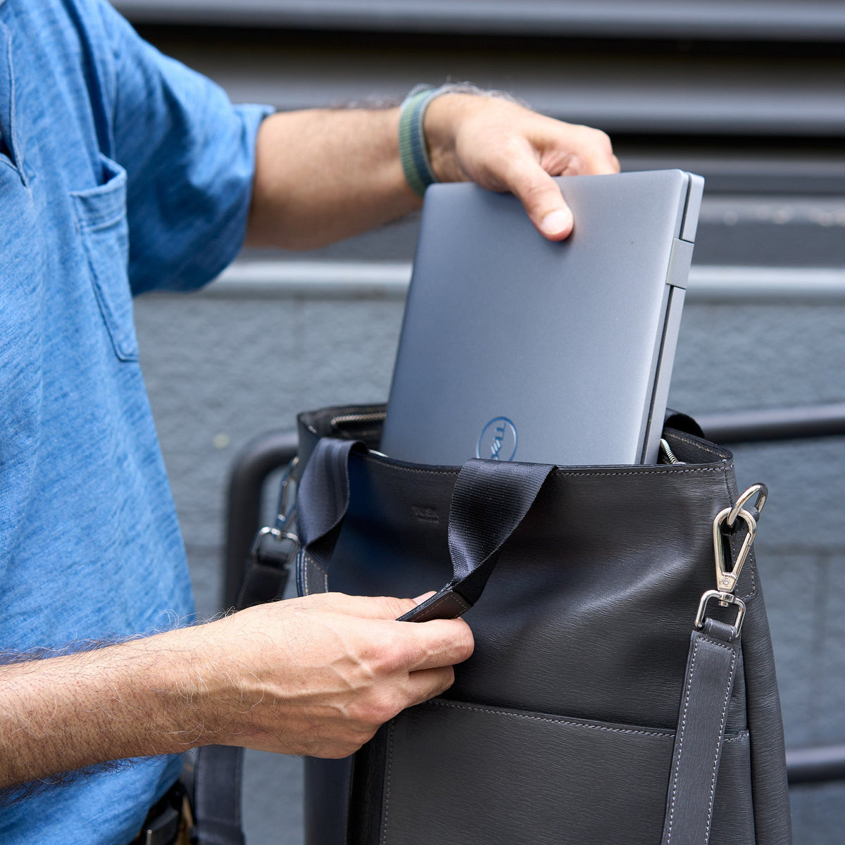 Person placing a laptop into a gray leather bag - CHARCOAL