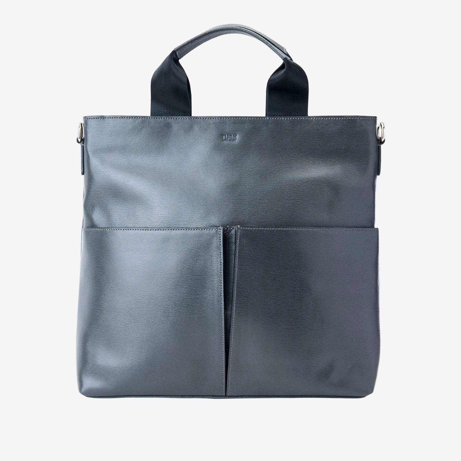 A dark gray leather tote bag with two top handles, a top zipper closure, and two large front slip pockets, shown against a plain white background - CHARCOAL