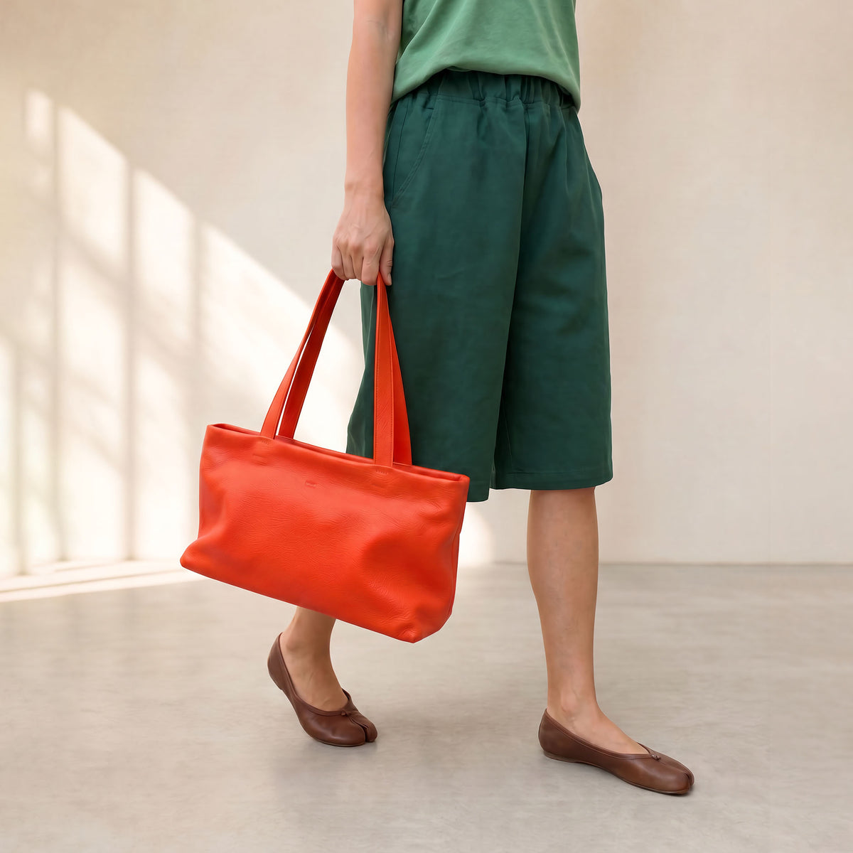 Woman walking holding orange leather top zip tote bag for everyday use with long shoulder straps  - ORANGE