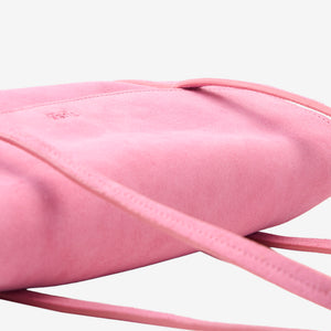 Close-up detail view of the blush pink Italian suede Vienatta | Jyoti shoulder bag, highlighting its soft suede texture, fine edge stitching, thin double shoulder straps, and the subtle embossed Tusk logo on the top flap against a plain light gray background - BLUSH