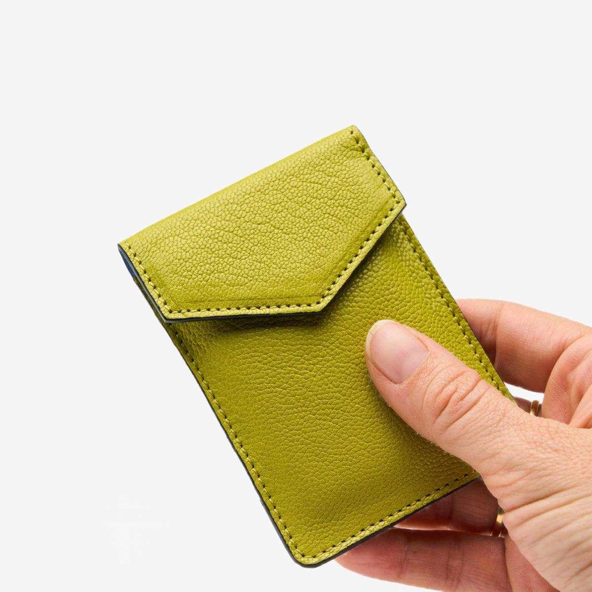 close up of hand holding green colored leather card case on white background - AVOCADO