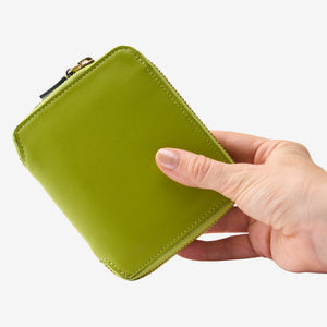 Tusk Lille medium leather zip-around wallet, shown in hand - AVOCADO