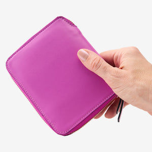 Tusk Lille medium leather zip-around wallet, shown in hand - MAGENTA