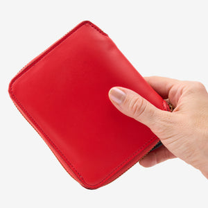 Tusk Lille medium leather zip-around wallet, shown in hand - RED