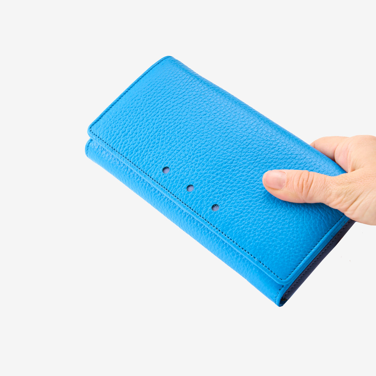 Tusk Ascot Flap Over Leather Wallet in Azure Blue held in hand, showcasing the premium pebbled leather grain and fold-over clutch design - AZURE